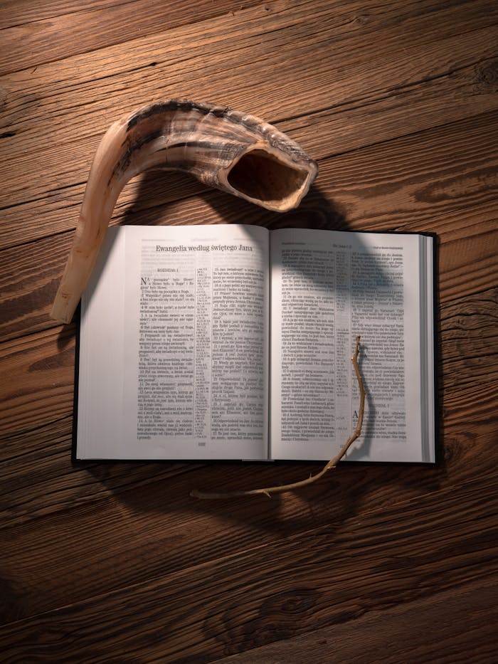 An open Holy Bible alongside a shofar horn on a wooden table, symbolizing religious faith.